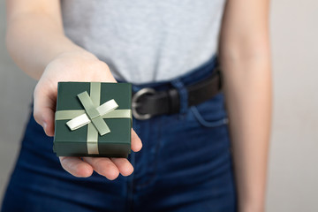 Female hand holding small box with a gift. Empty space