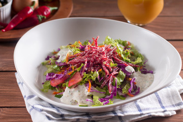 Mediterranean cuisine. Fresh salad with arugula, tomatoes, red cabbage, cucumber and yogurt sauce