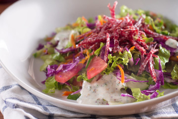 Mediterranean cuisine. Fresh salad with arugula, tomatoes, red cabbage, cucumber and yogurt sauce