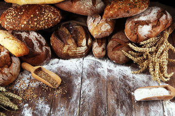 Different kinds of bread and bread rolls on board from above. Kitchen or bakery