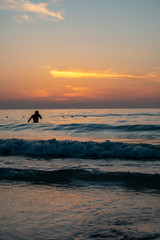 A man taking bath at beach during sunset