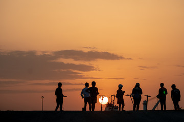 Fototapeta na wymiar Silhouette of teenagers with their E-bikes during sunset