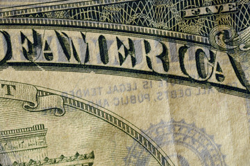 Close-up at America text, highly magnified surface of worn 5 dollars note with visible details of cotton fiber paper, with all flaws, watermarks and traces of usage.