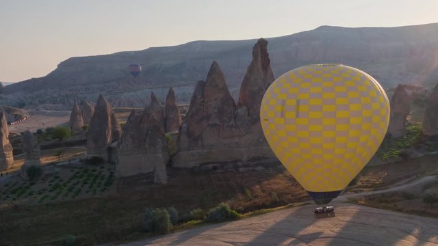 The span of a large yellow balloon, in a basket of people, close-up. Flying over the mountains - Panorama of Cappadocia at sunrise. Wide landscape of the valley of Goreme in Cappadocia. 4k. Aerial pho