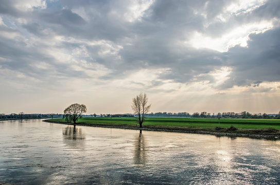 Looking upstream at the IJssel river from the waterfront of the town of Doesburg, The Netherlands under a dramatic sky on an afternoon in springtime