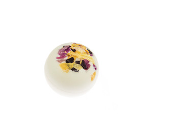 Creamy moisturizing small bath ball bomb with dry flower blossom petals isolated on white background, studio shot. 