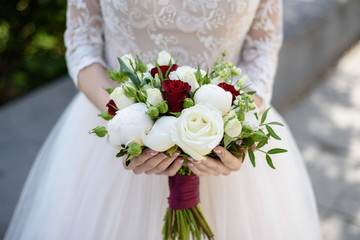 Wedding bouquet in hands and bride's dress