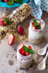 Homemade summer healthy breakfast. Greek yogurt with granola, pieces fresh strawberry on stone table. Copy space.