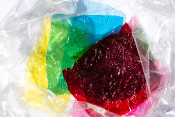 Thin sheet of multi coloured cellophane with shiny crumpled surface texture on white background,...