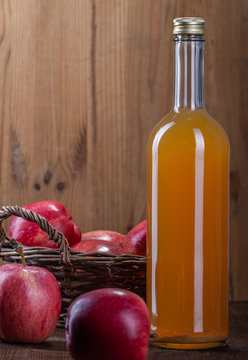 Sok jablkowy w szklanej butelce z naturalnym osadem. Swieze czerwone jablka.