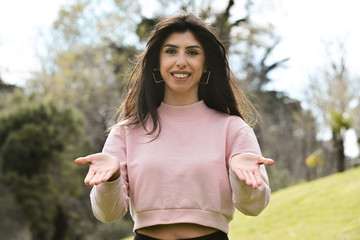 Attractive young woman enjoying her time outside in park with thanks with the expression on face