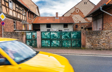 Stare zabudowania malego miasteczka w niemieckiej Bawarii, zabytkowa brama i jadacy samochod.
