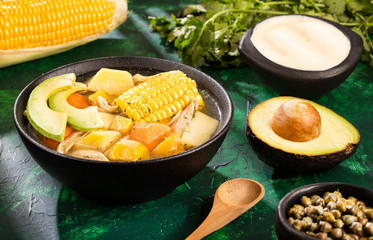 Colombian cuisine: ajiaco soup with chicken and vegetables close up in a bowl.