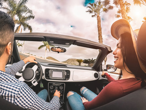 Happy young couple having fun during road trip in convertible car - Romantic lovers enjoying time together driving cabriolet auto in luxury vacation in a tropical city - Love and youth lifestyle
