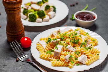 fusilli pasta with chicken breast and broccoli with chicken breast in white plate on Dark grey black slate background