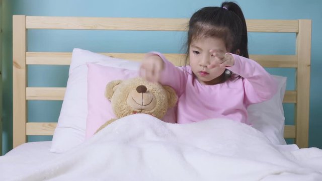 Happy child little asian girl sleeping with her teddy bear on the bed in her bedroom, Educational concept for homeschool