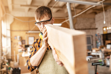 Man carpenter working with wooden workpieces at the construction site. Repair and job concept