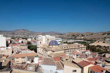 Fototapeta na wymiar picture taken from the castle of the municipality of petrer in the province of alicante, spain with houses, church of san bartolome and mountains in the background.