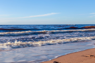 Golden yellow foamy sea waves background at romantic beach sunset with endless horizon