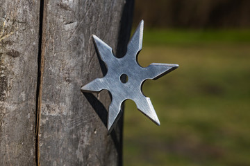 Shuriken (throwing star), traditional japanese ninja cold weapon stuck in wooden background