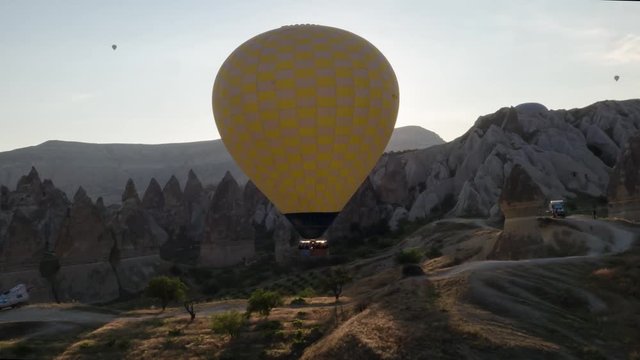 The span of a large yellow balloon, in a basket of people, close-up. Flying over the mountains - Panorama of Cappadocia through the sun's rays. Wide landscape of the valley of Goreme in Cappadocia. 4k