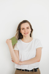 Portrait of succesful smiling woman in casual wear with green book on light background.