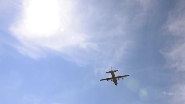 Lockheed C-130 Hercules flying above in blue sky
