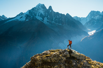 A hiker on top of a rocky summit in the mountains of the Alps - Powered by Adobe
