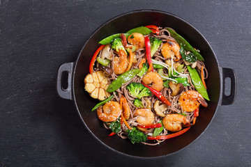 Stir fried noodles with shrimps and vegetables in a wok, top view