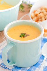Pumpkin soup in a blue enameled mug, selective focus