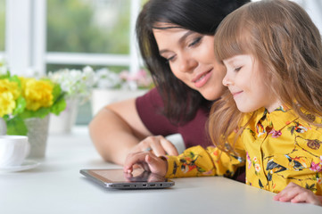 Portrait of mother and daughter playing game on laptop