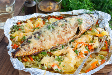 Baked mackerel with vegetables - potatoes, carrots, onions, green peas, top view