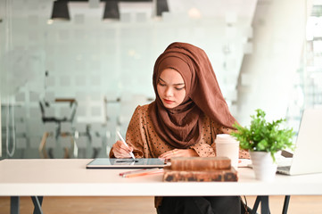 Islam woman working with digital tablet and pen on office workplace.
