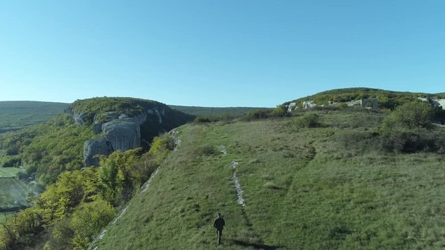 Man walking on top of hill under blue sky. Shot. Wonderful view from the top