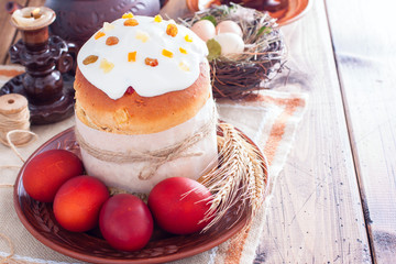 Kulich, traditional Easter pastry on a wooden table with painted eggs, horizontal, copy space