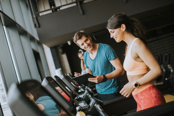 Close up of woman with trainer working out on treadmill in gym