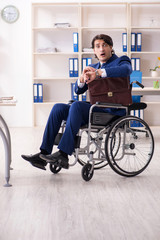 Young male employee in wheelchair working in the office 
