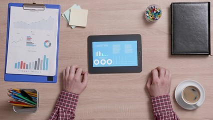 Above shot of a man using a data analysys application on his tablet. Office and corporate concept. Company data verify.