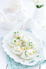 Snack of eggs under mayonnaise on a white plate, selective focus