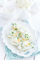 Snack of eggs under mayonnaise on a white plate, selective focus