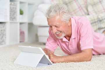 Portrait of beautiful senior man using tablet at home