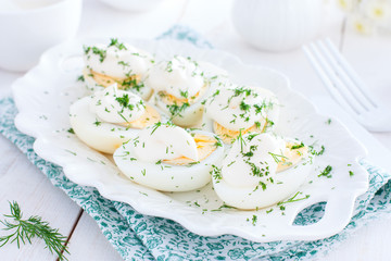 Cold snack of boiled eggs with mayonnaise on a white plate, horizontal