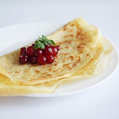 Delicious homemade pancakes with fresh berries on a white background.