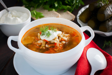 Soup with pickled cucumbers and pearl barley - rassolnik on a wooden background,horizontal