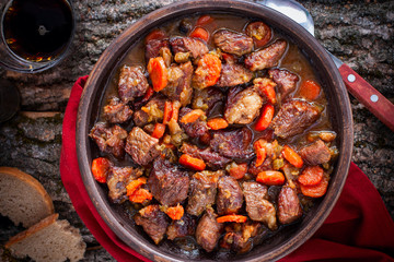 Stewed beef with carrots and onions in pottery, top view, horizontal