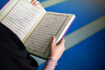 Close up view of muslim woman reading the holy Al Quran inside a mosque