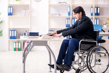 Young male employee in wheelchair working in the office 