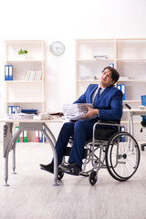 Young male employee in wheelchair working in the office 