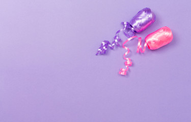 Obraz na płótnie Canvas Spool of party streamers ribbon on a purple paper background
