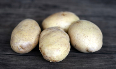 Yellow potatoes on wood background.